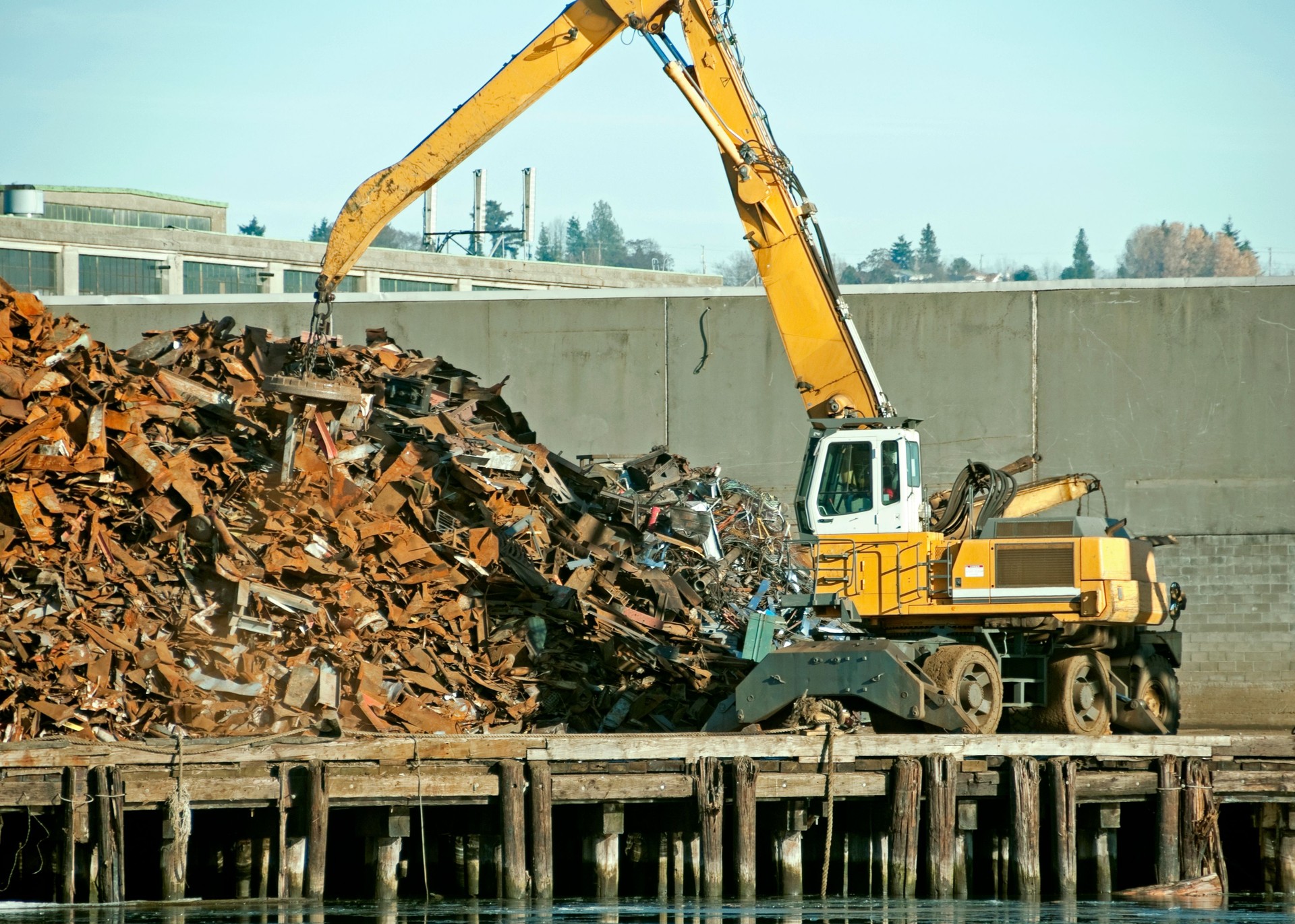 Crane with magnet moving scrap metal onto pile
